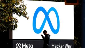 A pedestrian walks in front of a new logo and the name 'Meta' on the sign in front of Facebook headquarters on October 28, 2021 in Menlo Park, California.